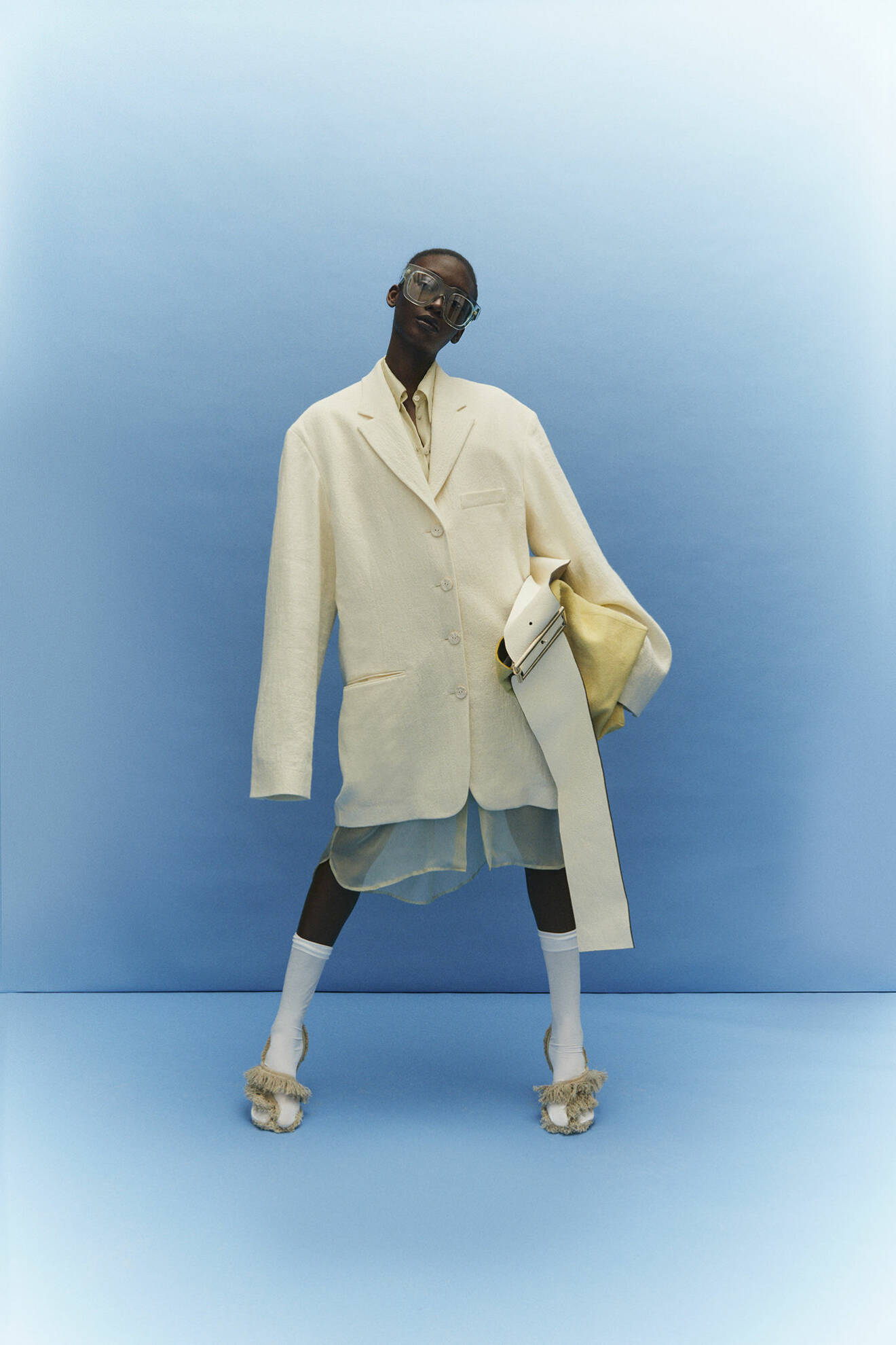 Modellen bär kavaj, skjorta, klänning, väska, skor och solglasögon från Acne Studios.