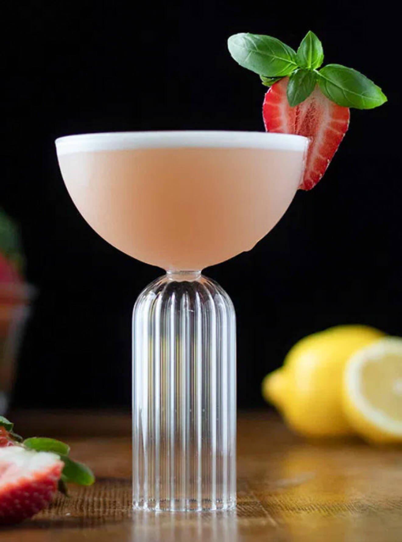 skummig drink i högt glas med jordgubb och basilika