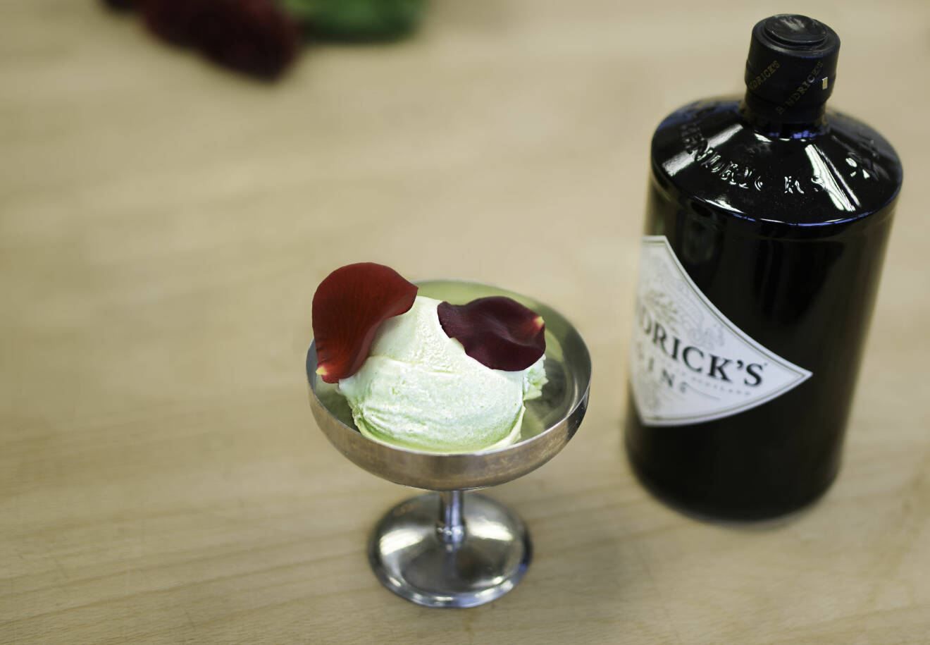 Glass med rosenblad och en flaska gin