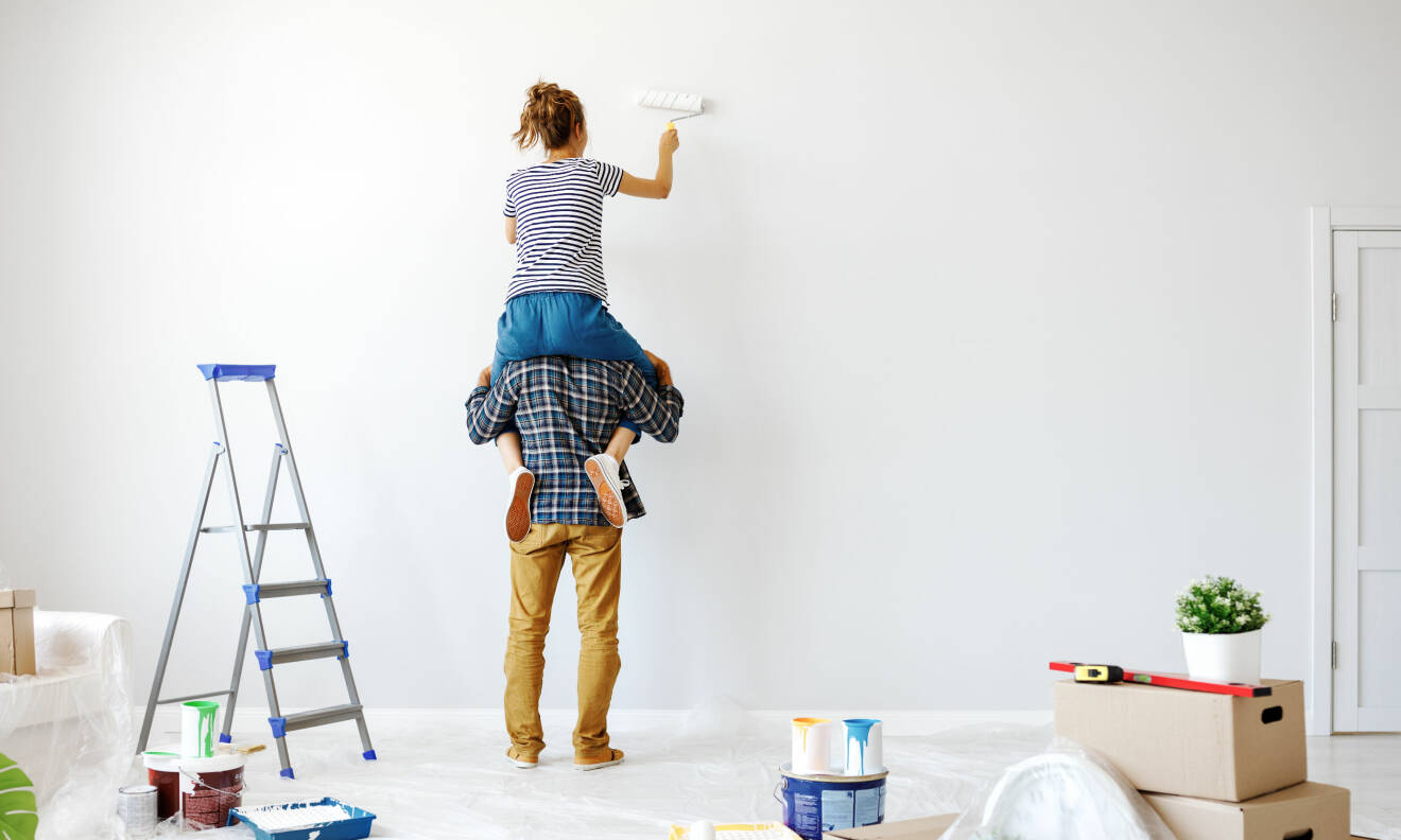 Kvinna på en mans axlar som målar om väggen