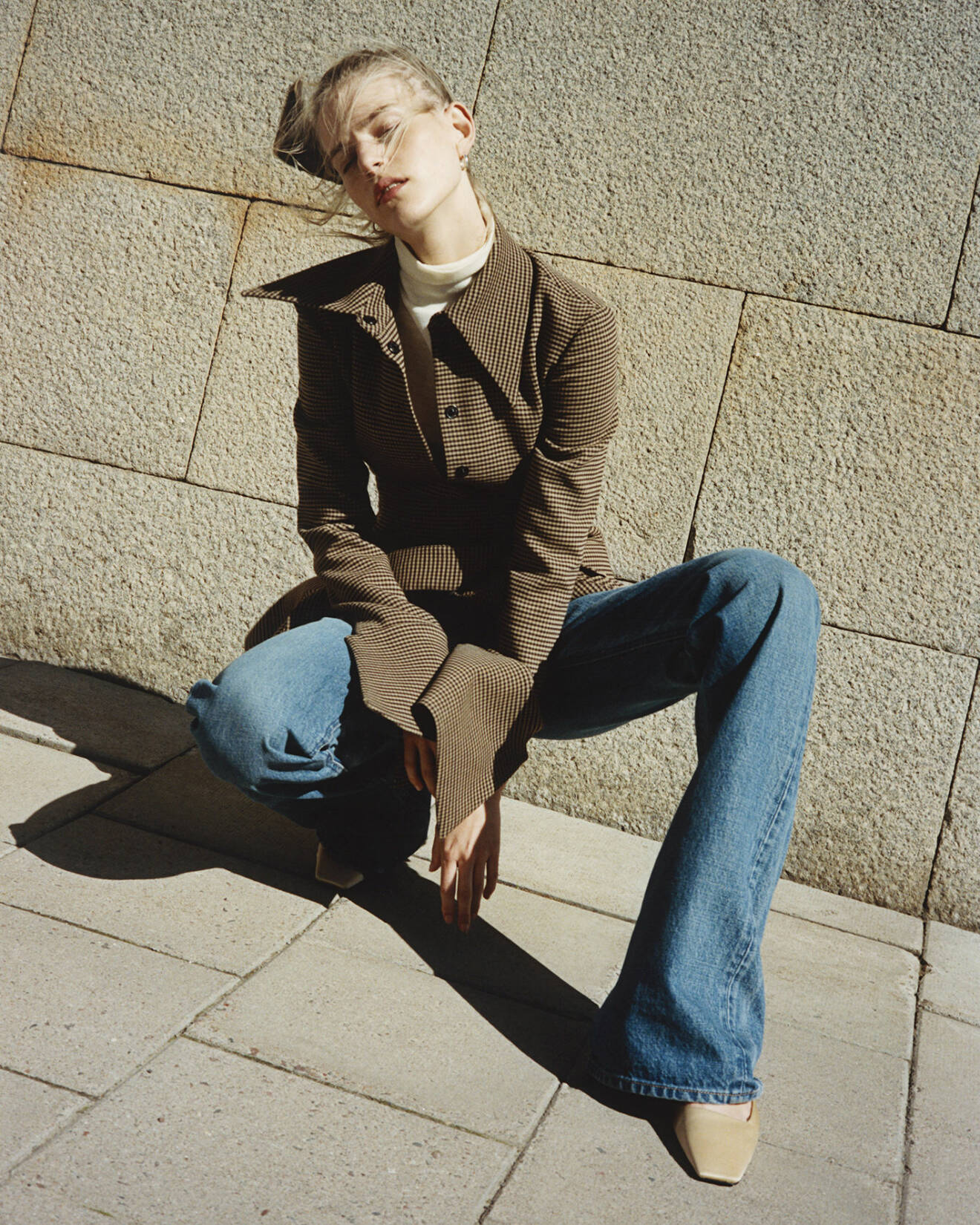 Modellen bär en rutig skjortblus från AWAKE Mode och jeans från Celine by Heidi Slimane