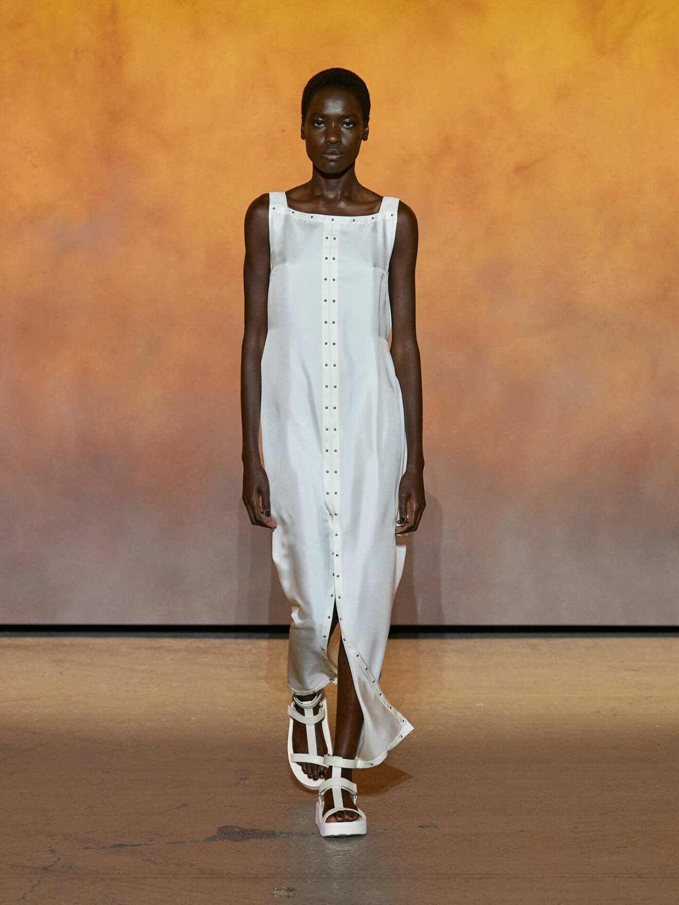 Lång vit klänning med vita sandaler från Hermès.