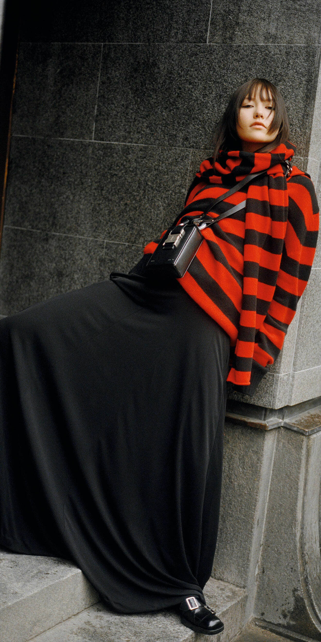 Modellen har på sig en randig tröja i rött och svart tillsammans med en svart långkjol