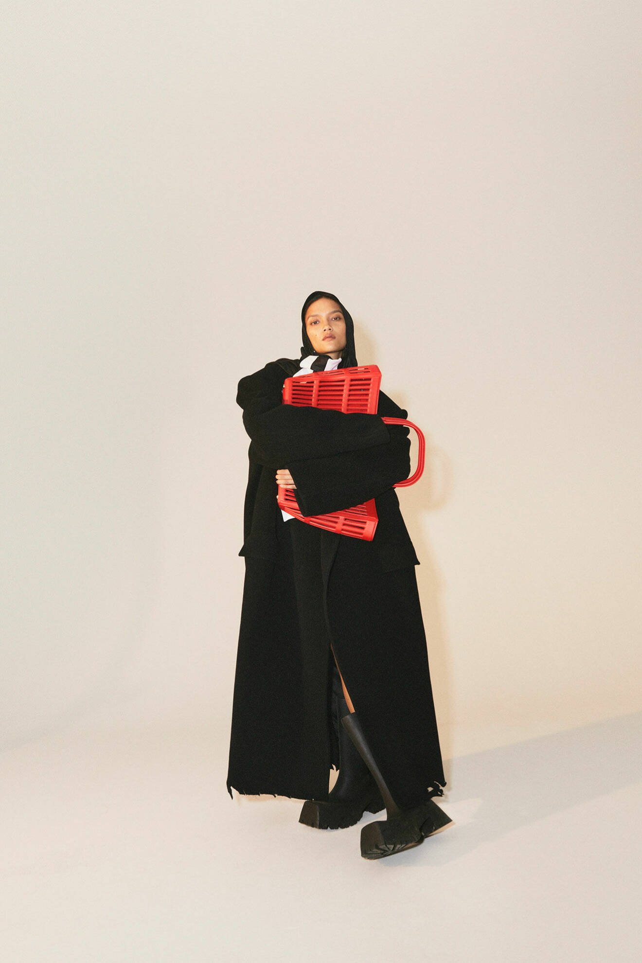 Modellen bär en svart kappa, scarf och röd väska, allt från Balenciaga