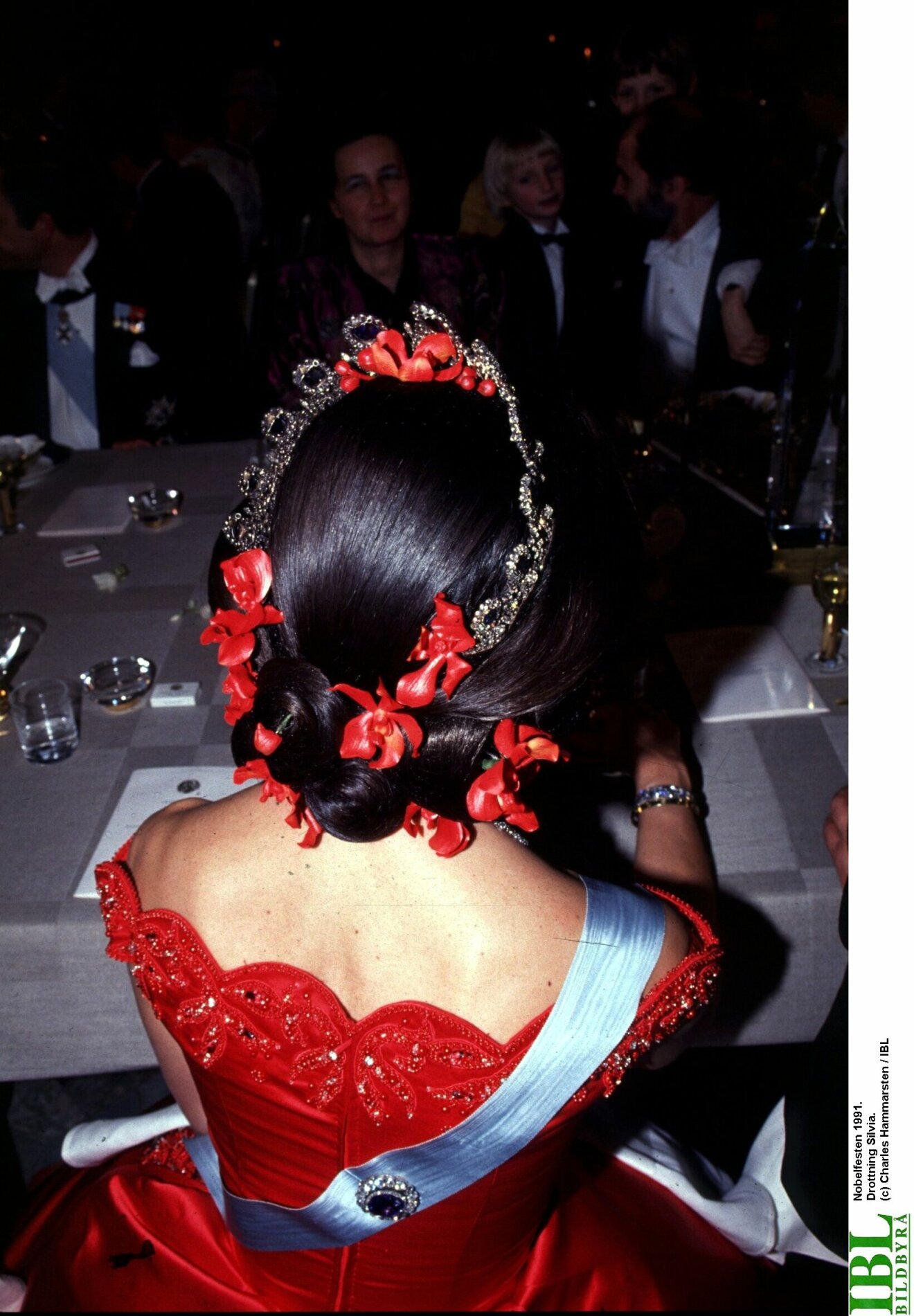 Drottning Silvia med röda blommor i håret.