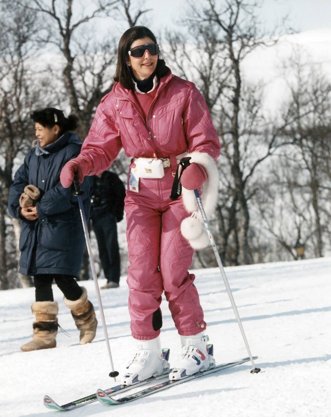 Drottning Silvia i skidbacken klädd i en rosa overall och midjeväska.