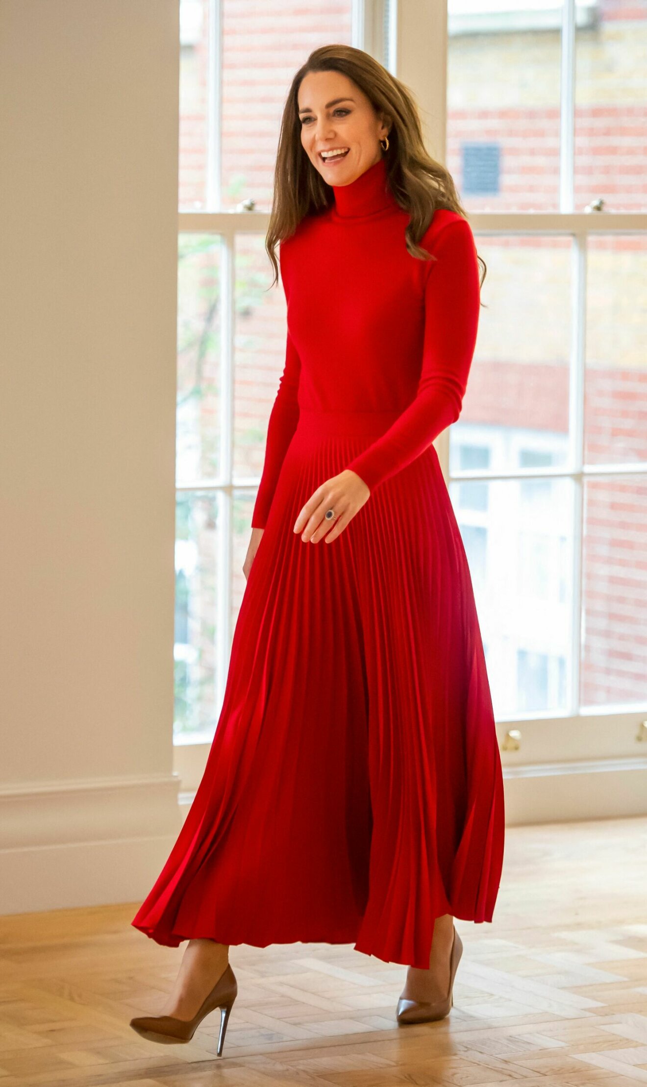 Kate i röd polotröja och plisserad kjol.