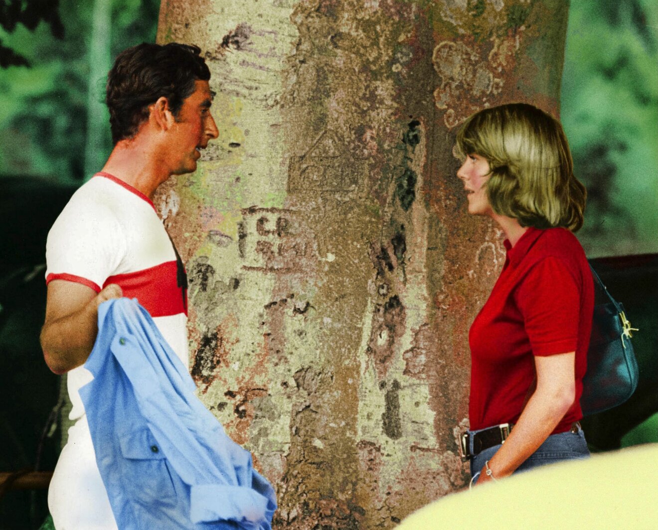 Prins Charles och Camilla står och pratar bakom ett träd.