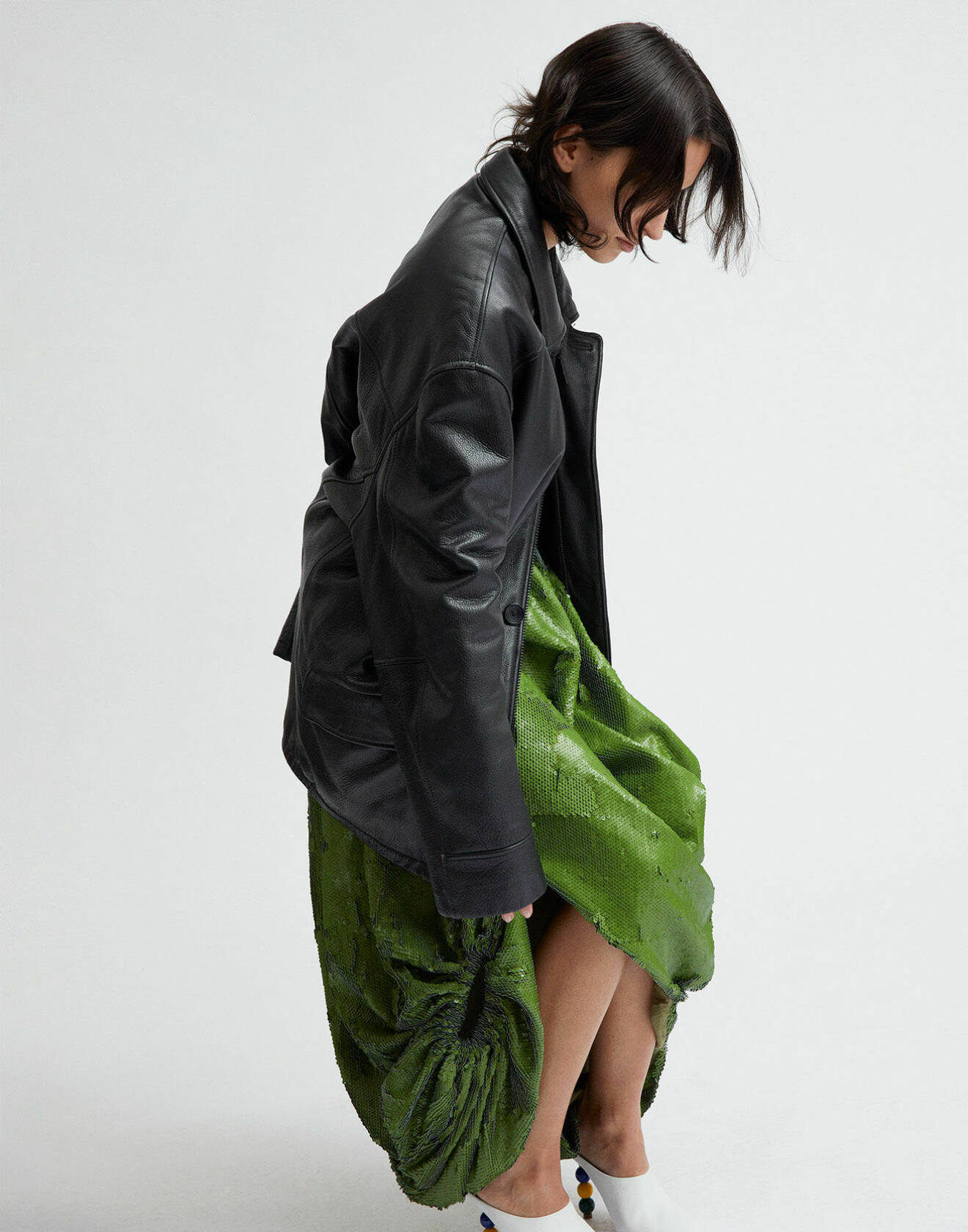 Modellen har på sig en grön kjol av återvunnen polyester och en svart skinnjacka