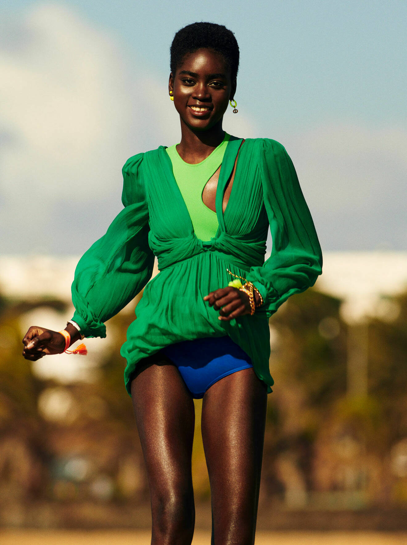 Modellen har på sig en mörkgrön klänning med en ljusgrön topp under och blåa bikinitrosor