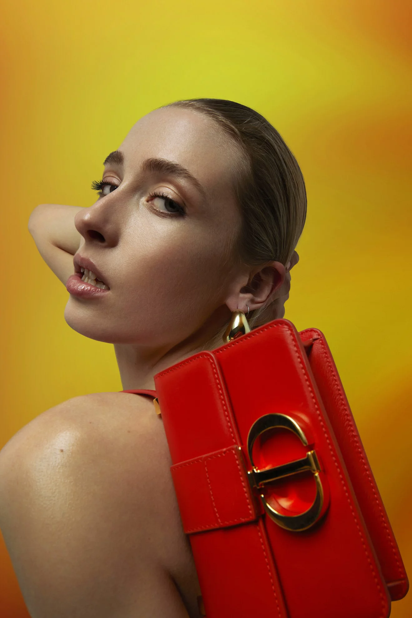 Närbild på modellen som håller i en röd väska från Dior