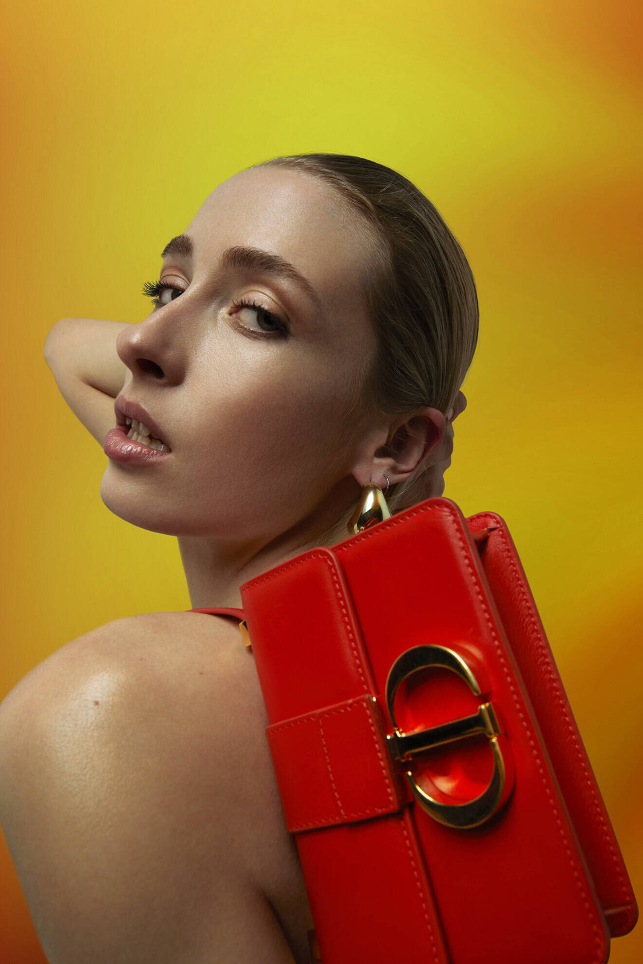 Närbild på modellen som håller i en röd väska från Dior