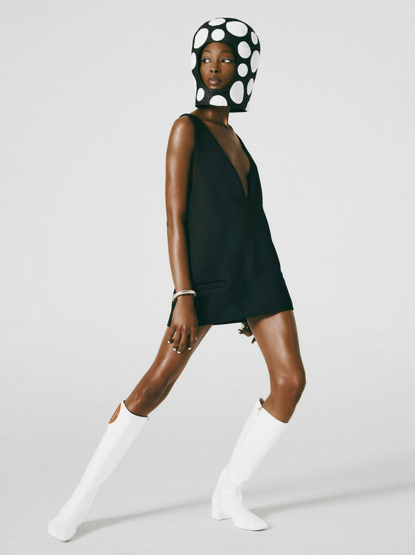 Modellen bär en svart klänning och vita boots, båda från Dior, tillsammans med en svart hjälm med vita prickar från Eric Javits