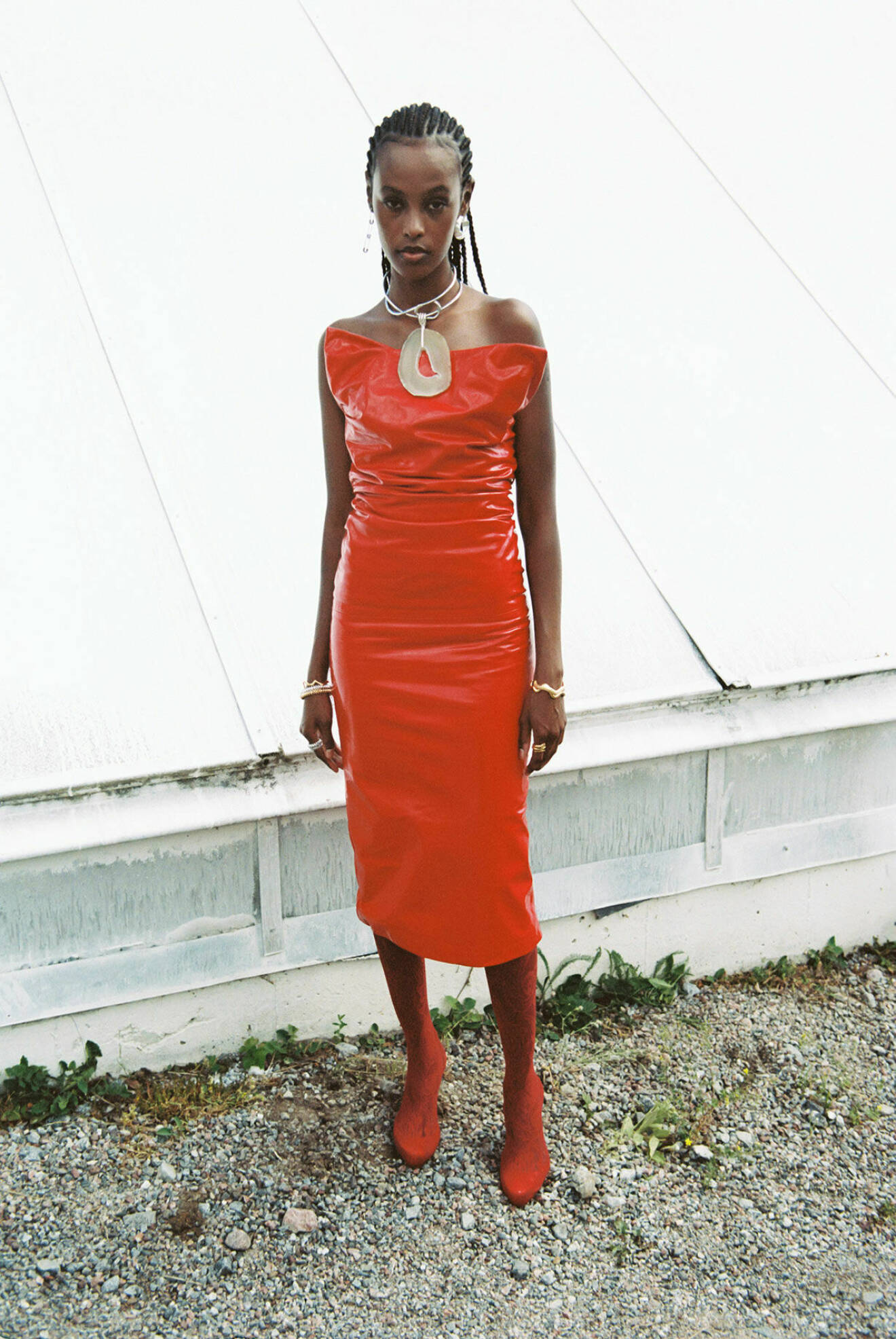 Fotomodellen bär en knälång röd klänning från Sportmax tillsammans med vintage strumpbyxor.
