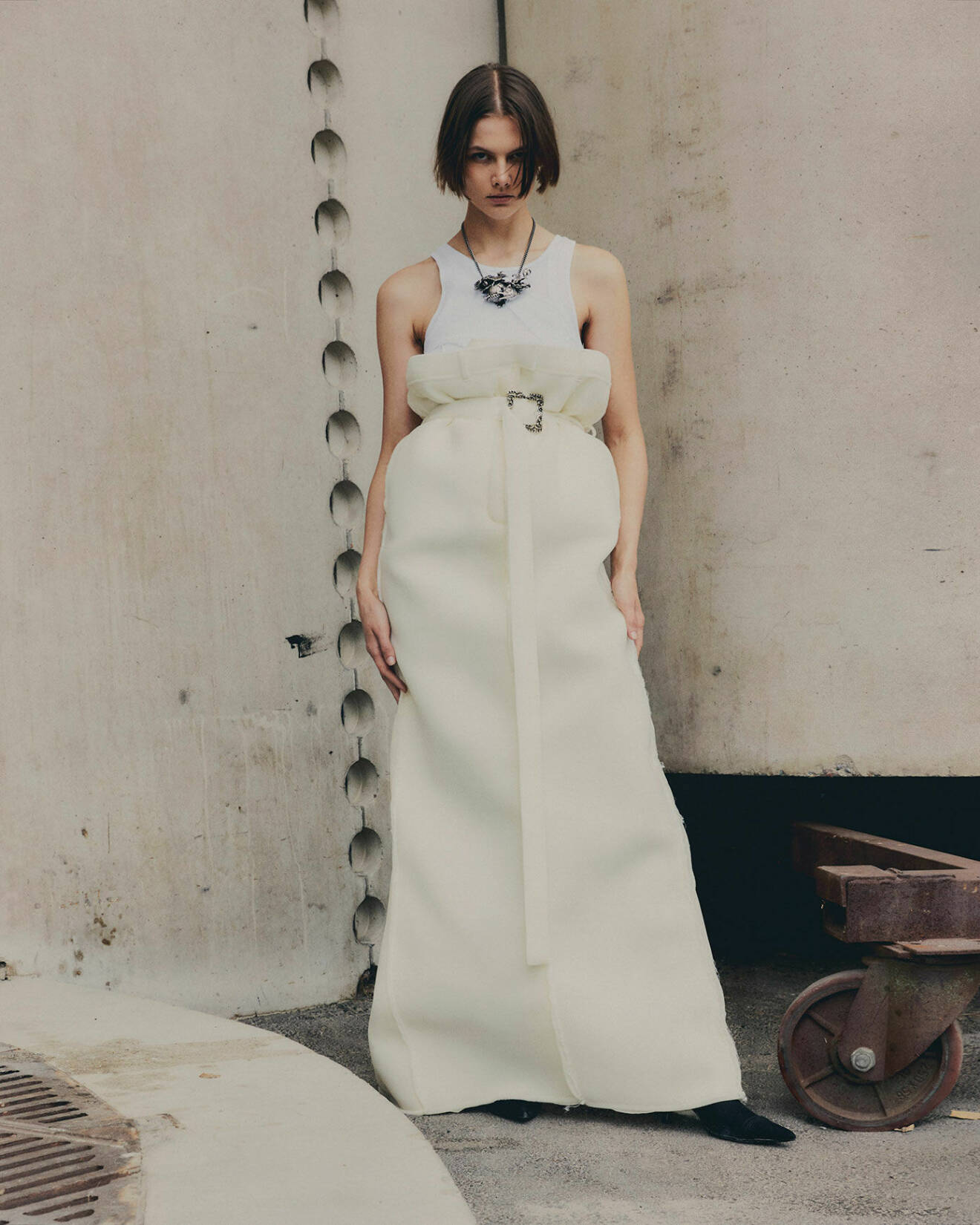 Fotomodellen har på sig ett vitt linne och lång, vit kjol samt halsband, allt från Acne Studios