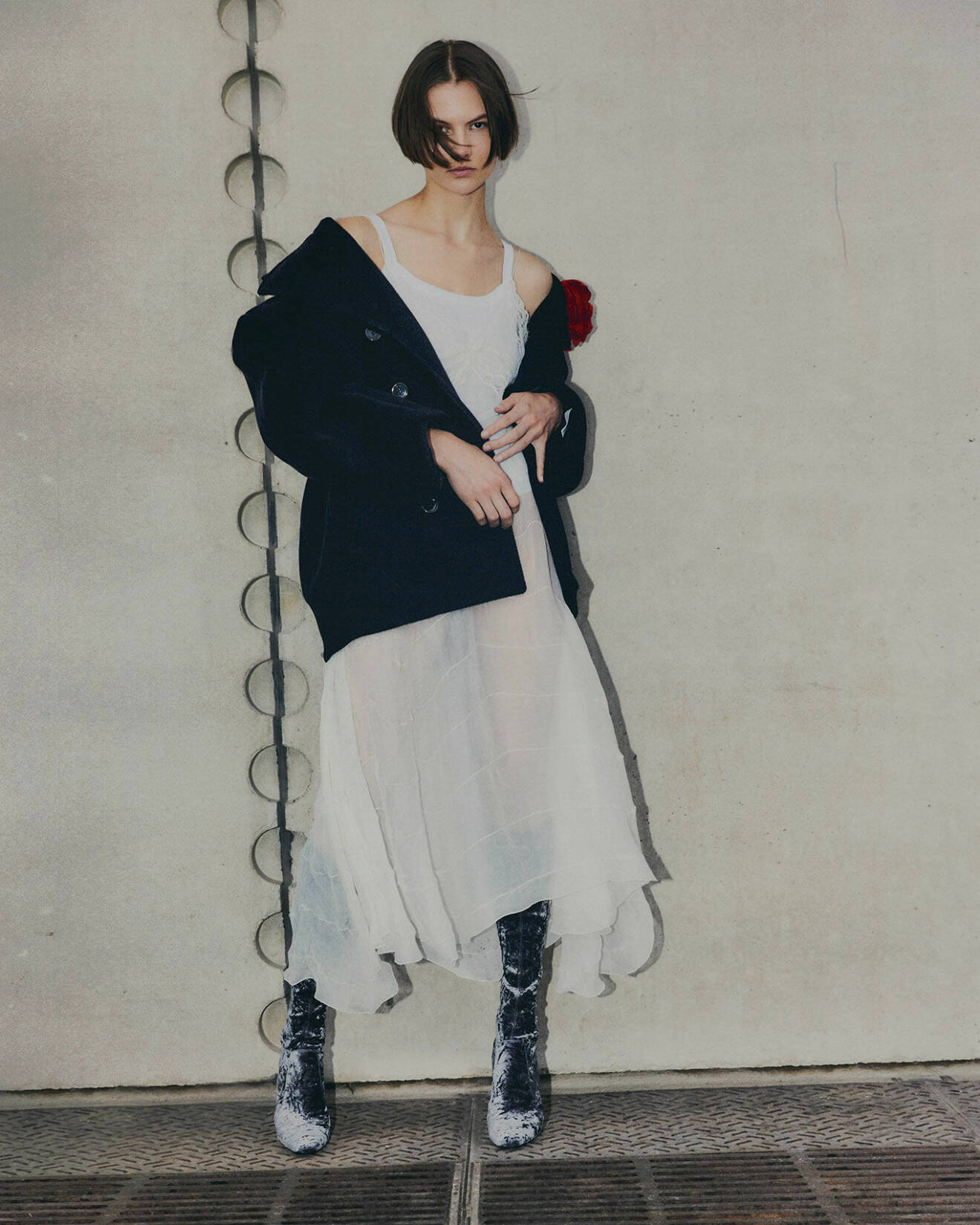 Modellen bär en vit klänning med en svart kappa över, båda från Saint Laurent