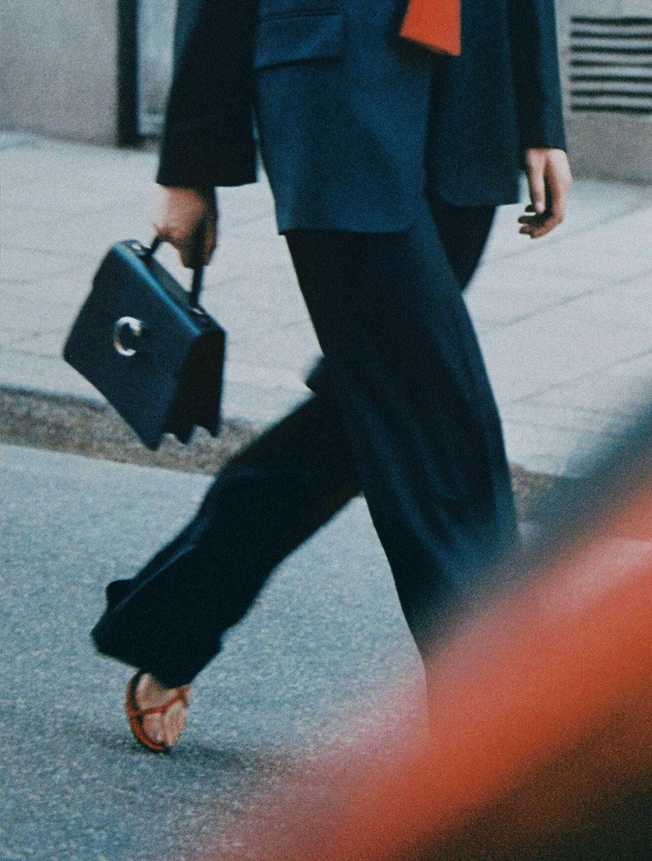Modellen har på sig en svart kavaj och svarta byxor från Filippa K samt en svart handväska från Cartier