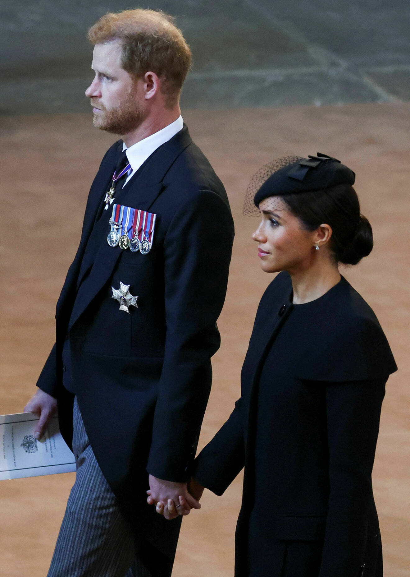 Prins Harry och Meghan Markle hand i hand under begravningen.