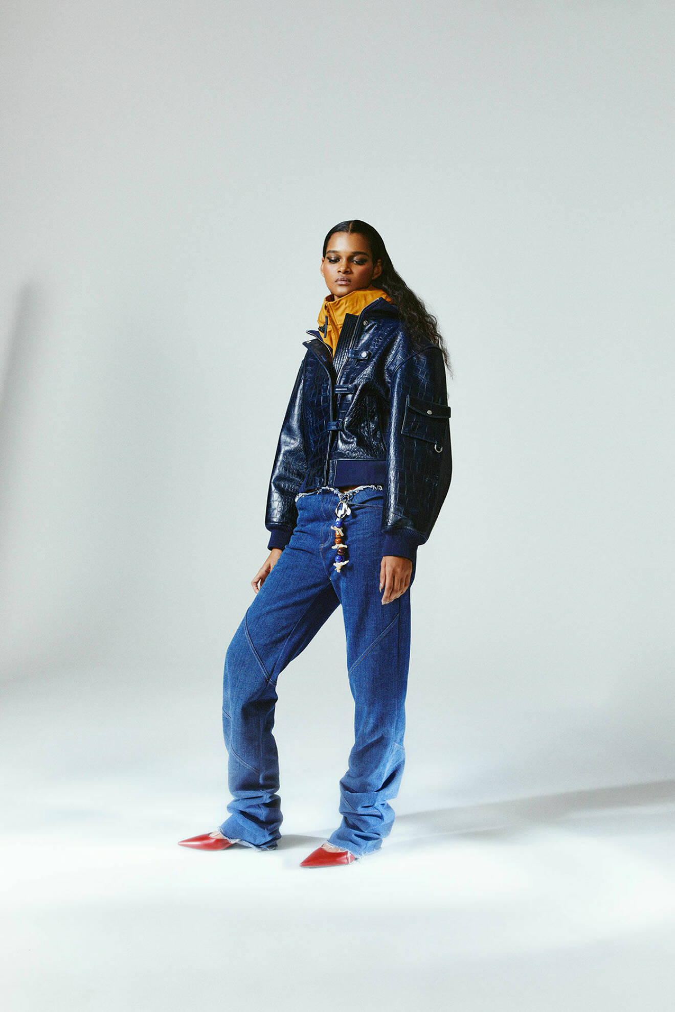 Modellen bär en blå vindjacka från Lundhags med en gul skinnjacka från Saks Potts under, samt jeans från Jade Cropper.