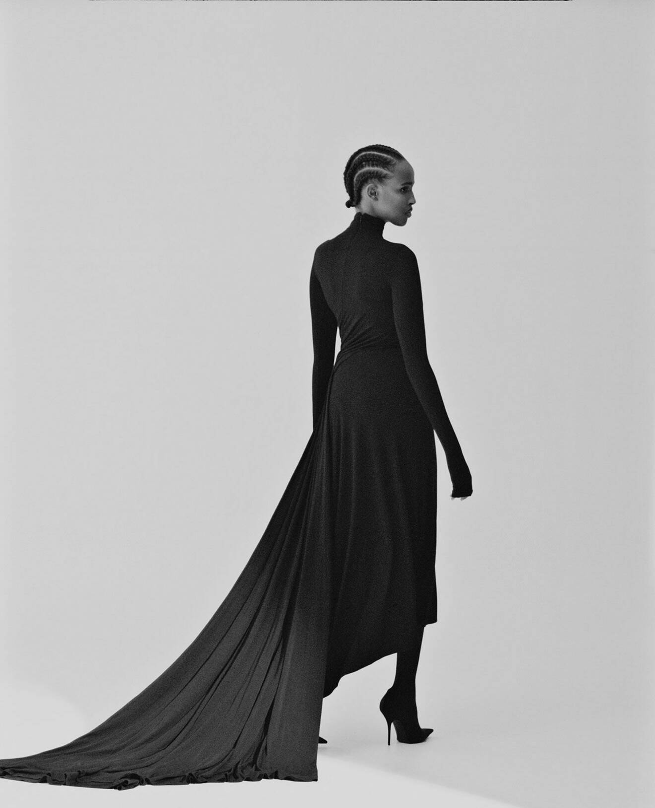 Modellen bär en svart klänning med släp och långa ärmar tillsammans med svarta skor, allt från Balenciaga.