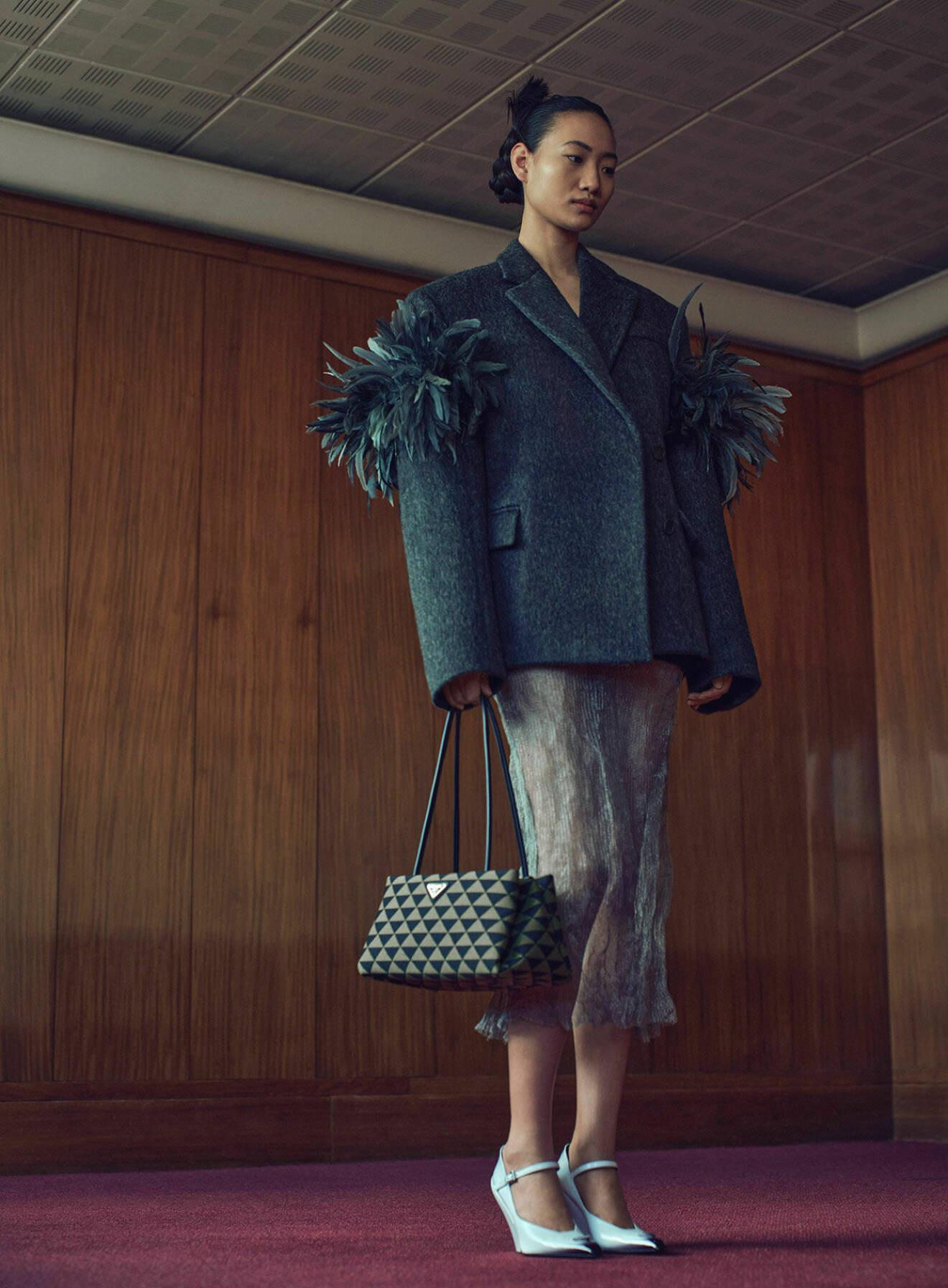 Modellen bär en kavaj, kjol, väska och pumps, allt i en stilkrock från Prada.