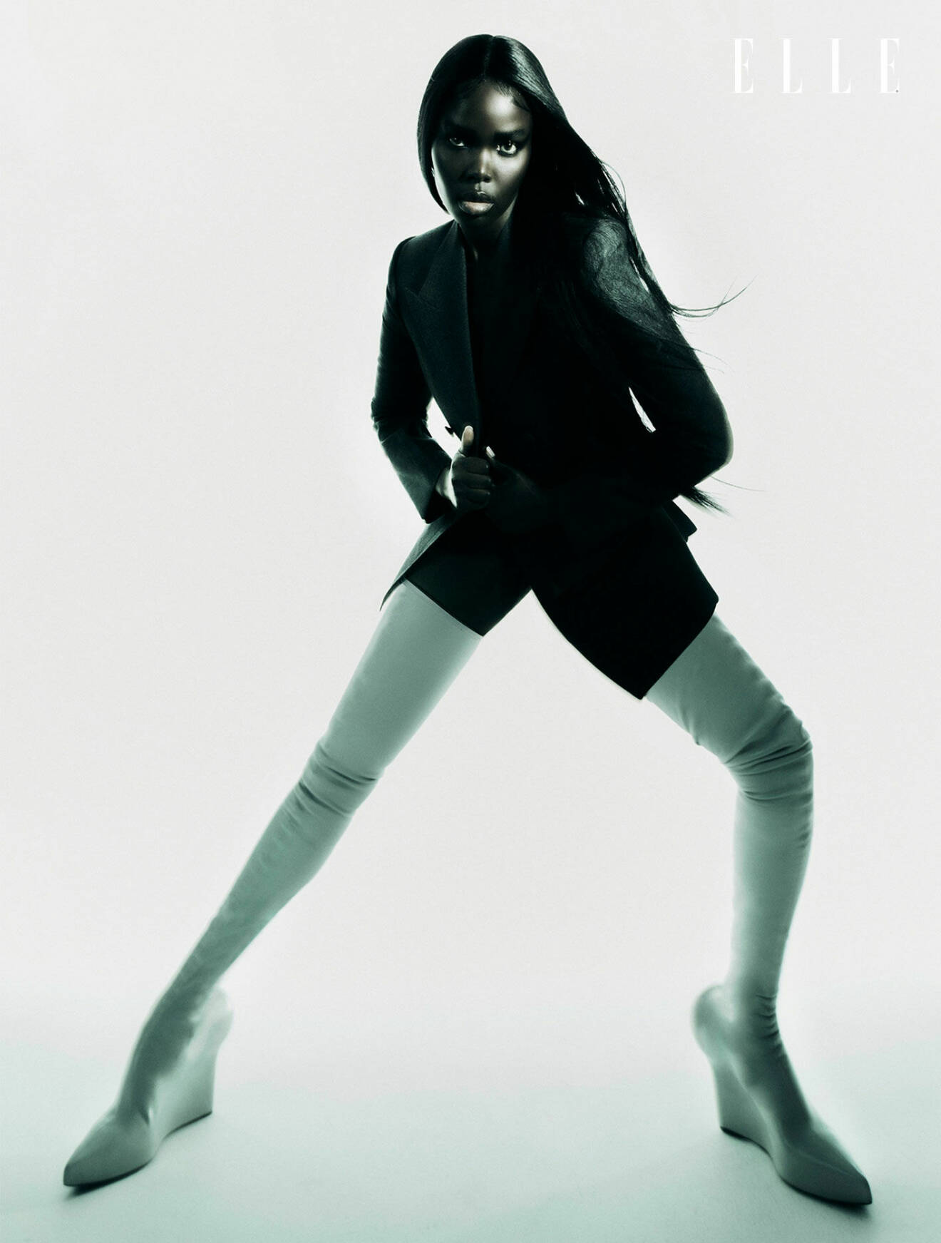 Modellen bär en svart kavaj och vita lårhöga boots, allt från Givenchy.