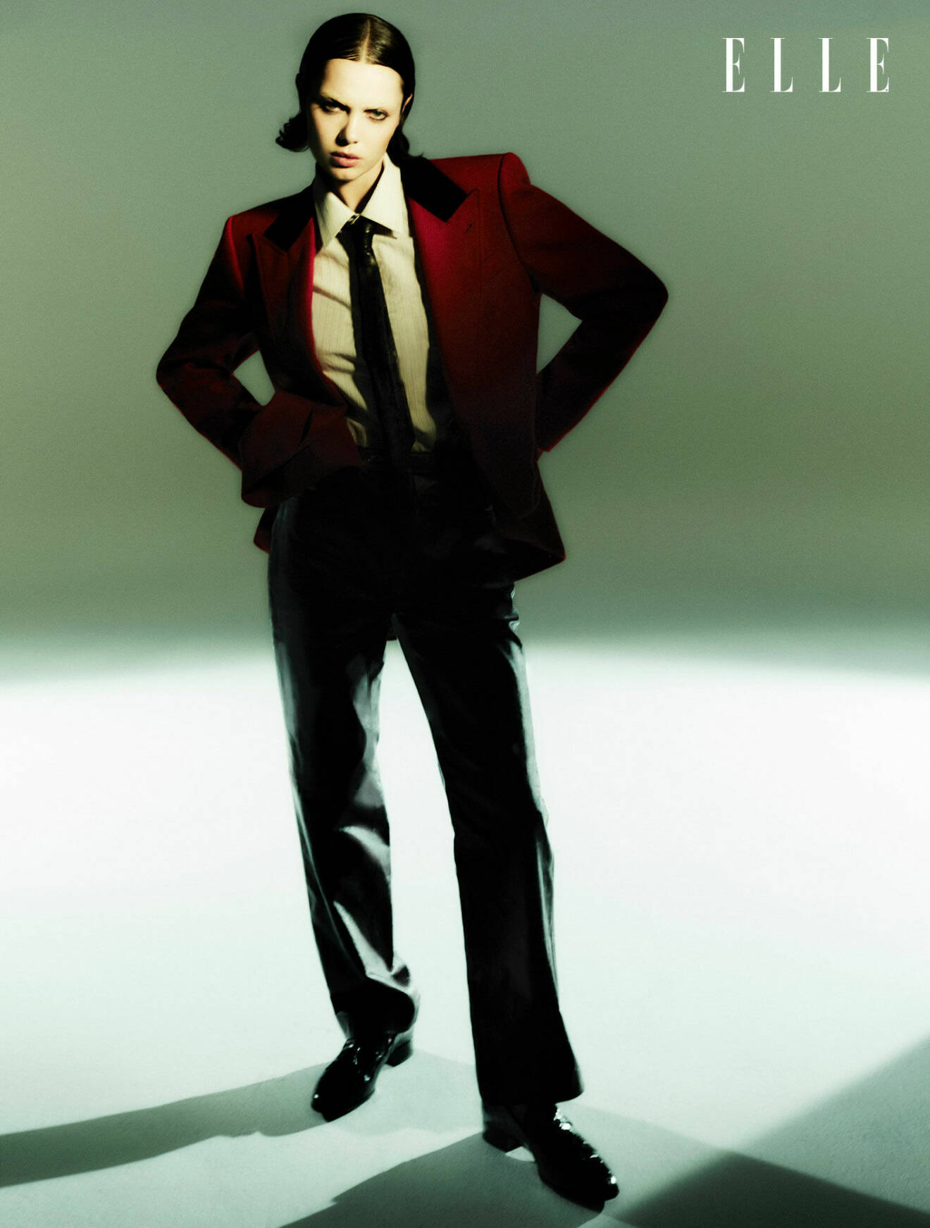 Modellen bär en röd kavaj med en vit skjorta, svart slips och byxor, allt från Gucci.