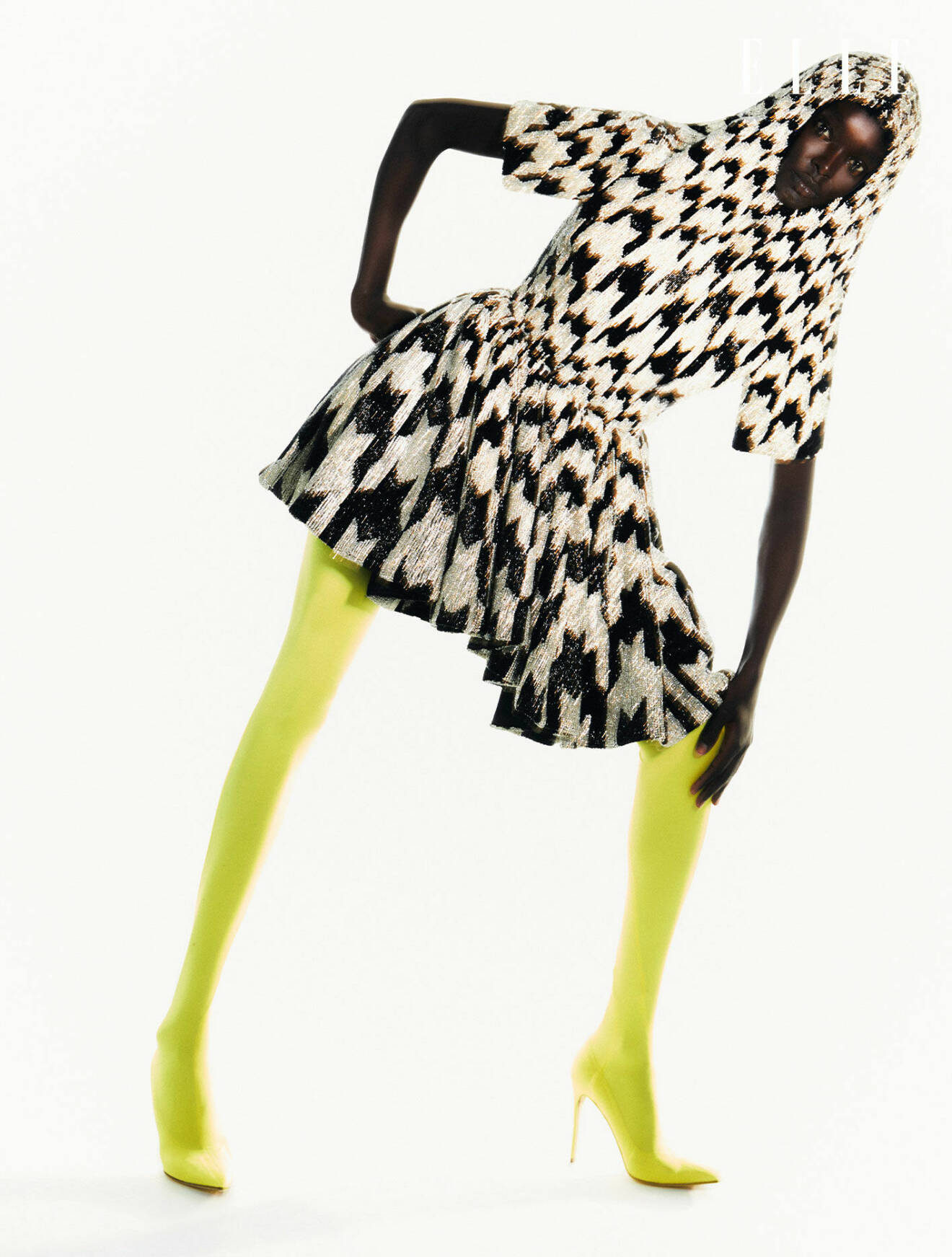 Modellen har på sig en mönstrad klänning med luva och gula boots från Richard Quinn.