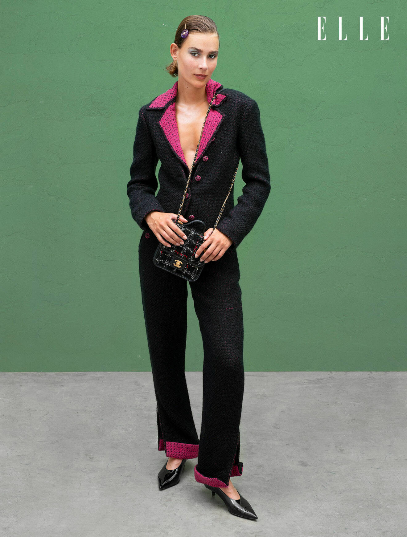 Modellen har på sig en svart kavaj med rosa detaljer tillsammans med matchande byxor, allt från Sportmax.