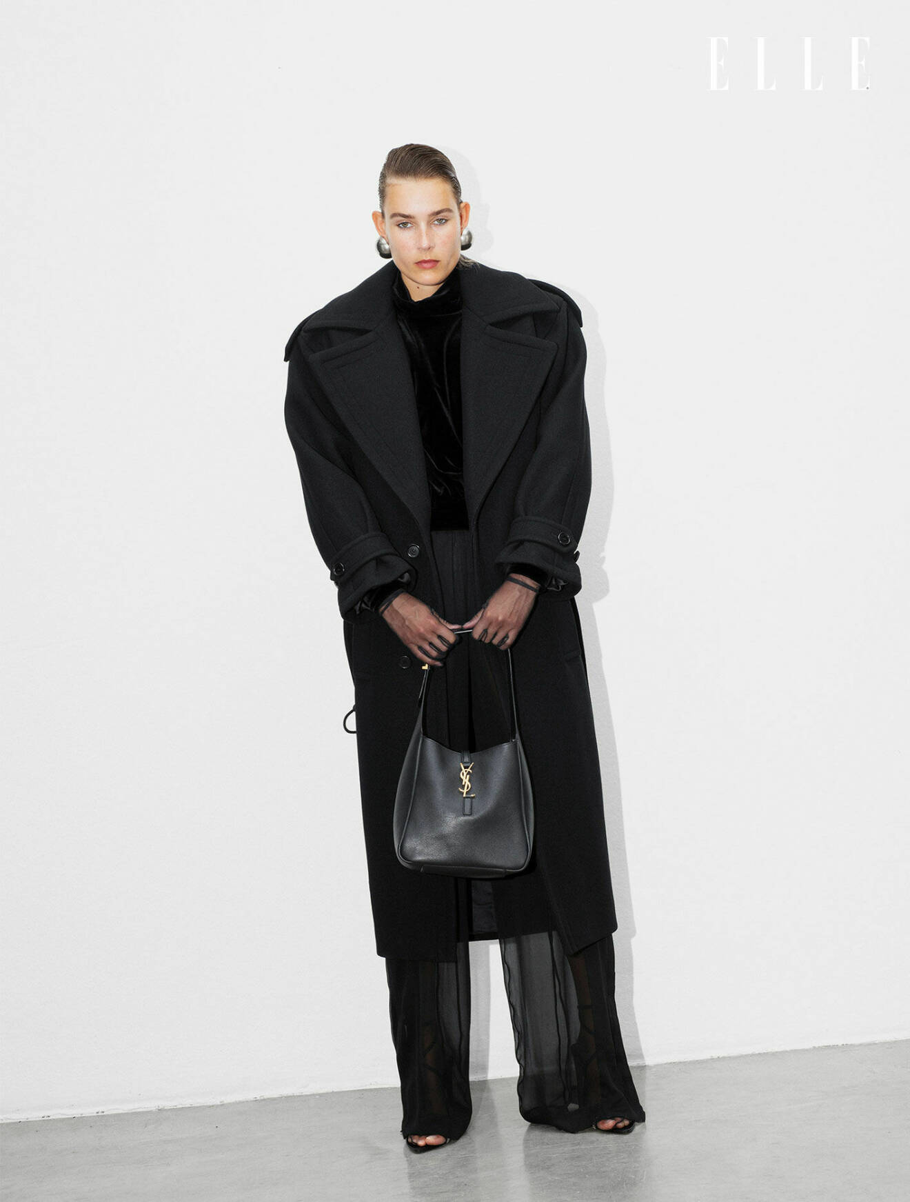 Modellen har på sig en lång kappa, tröja och byxor, allt från Saint Laurent by Anthony Vaccarello.