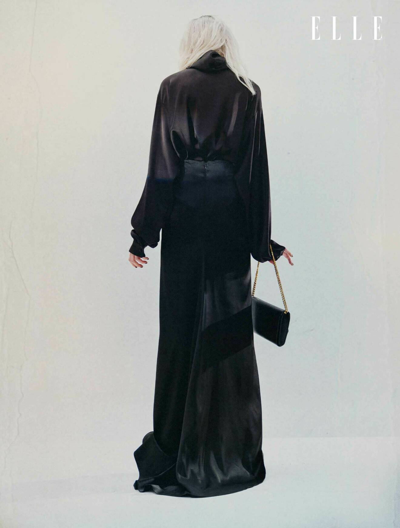 Modellen har på sig en svart blus, kjol och väska, allt från Balenciaga.