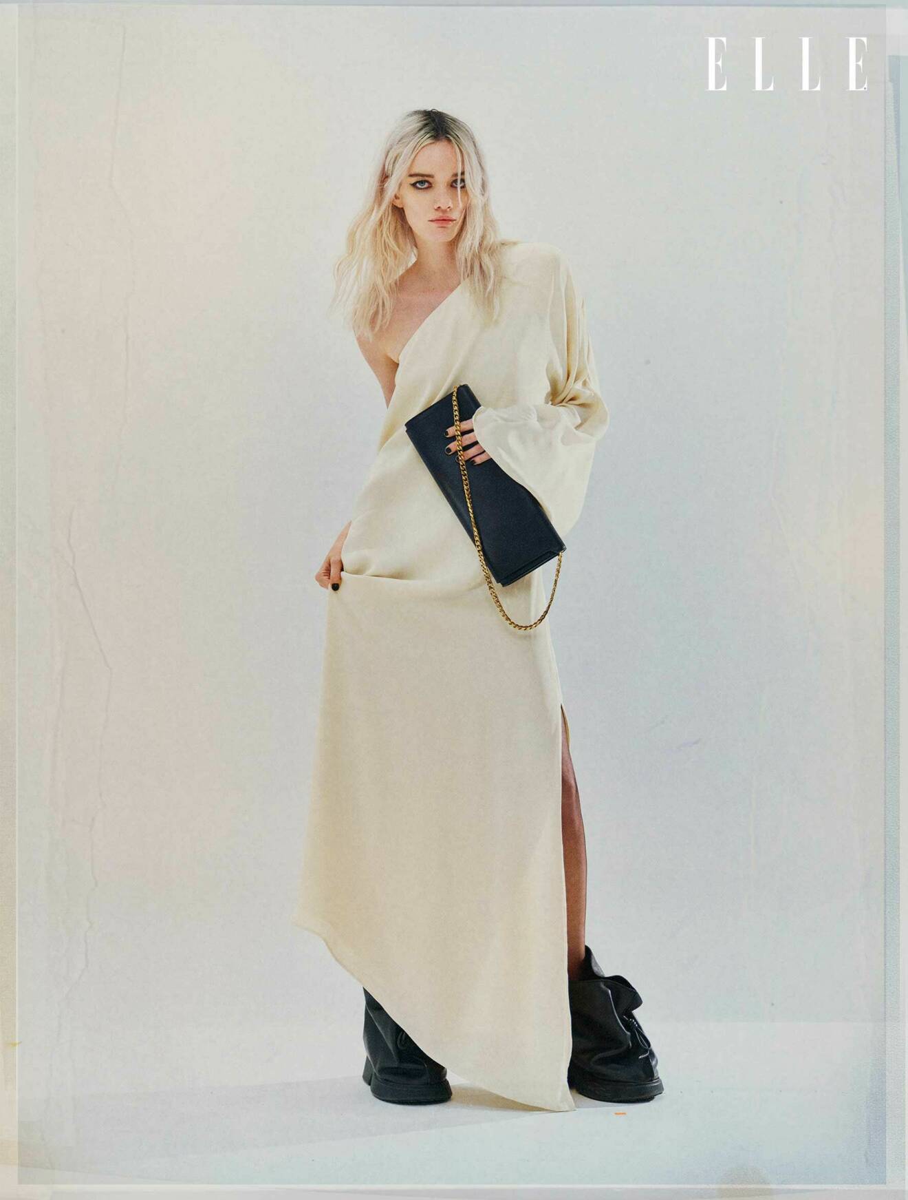 Modellen bär en lång vit klänning från By Malene Birger och en svart handväska från Balenciaga.