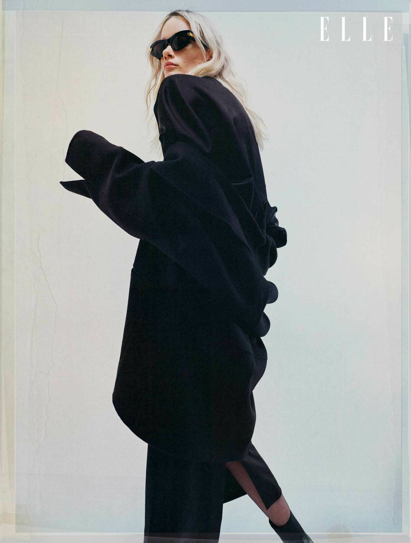 Fotomodellen har på sig en svart kappa och lång svart klänning från Totême.