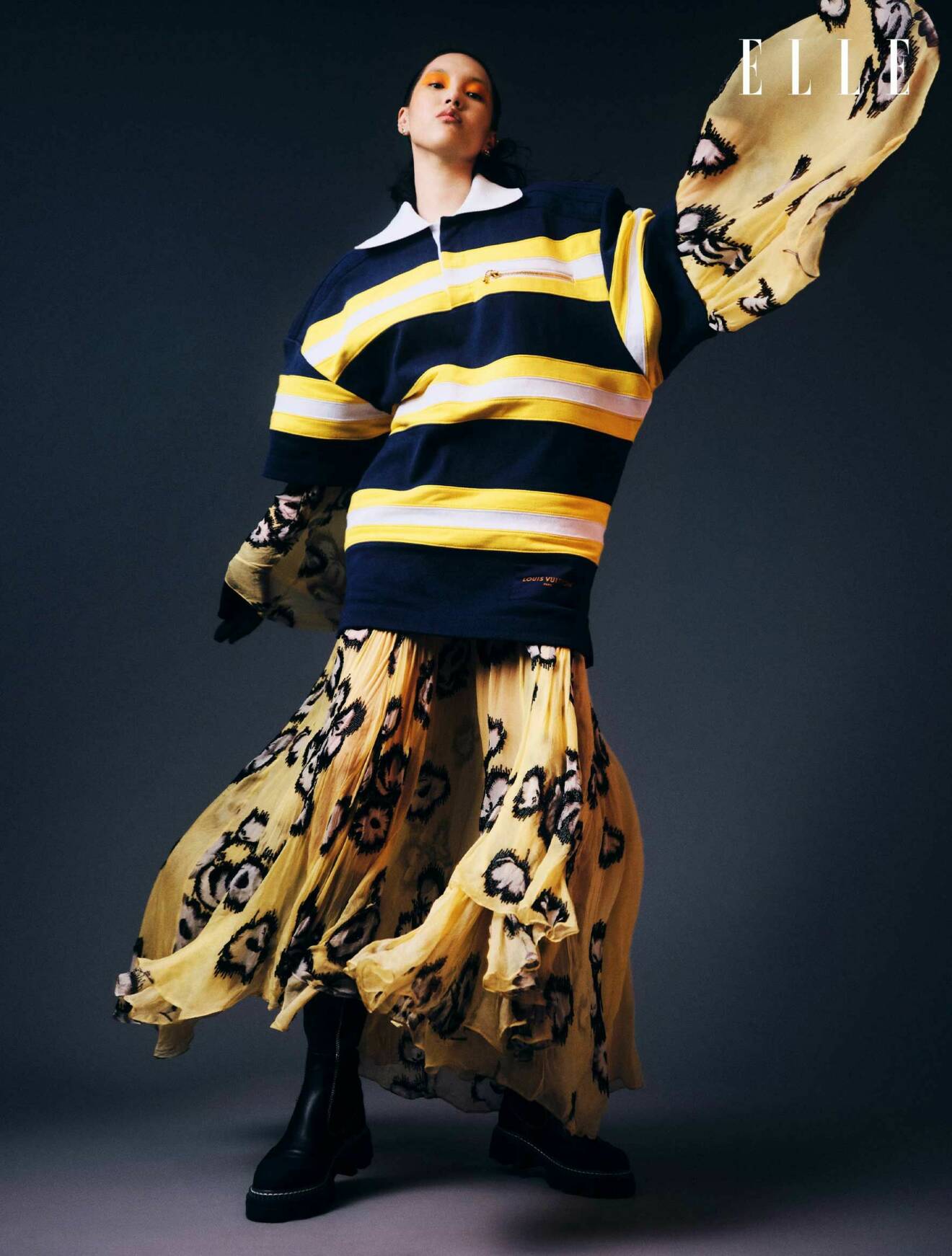 Fotomodellen har på sig en randig klänning över en gul klänning med mönster, båda från Louis Vuitton.