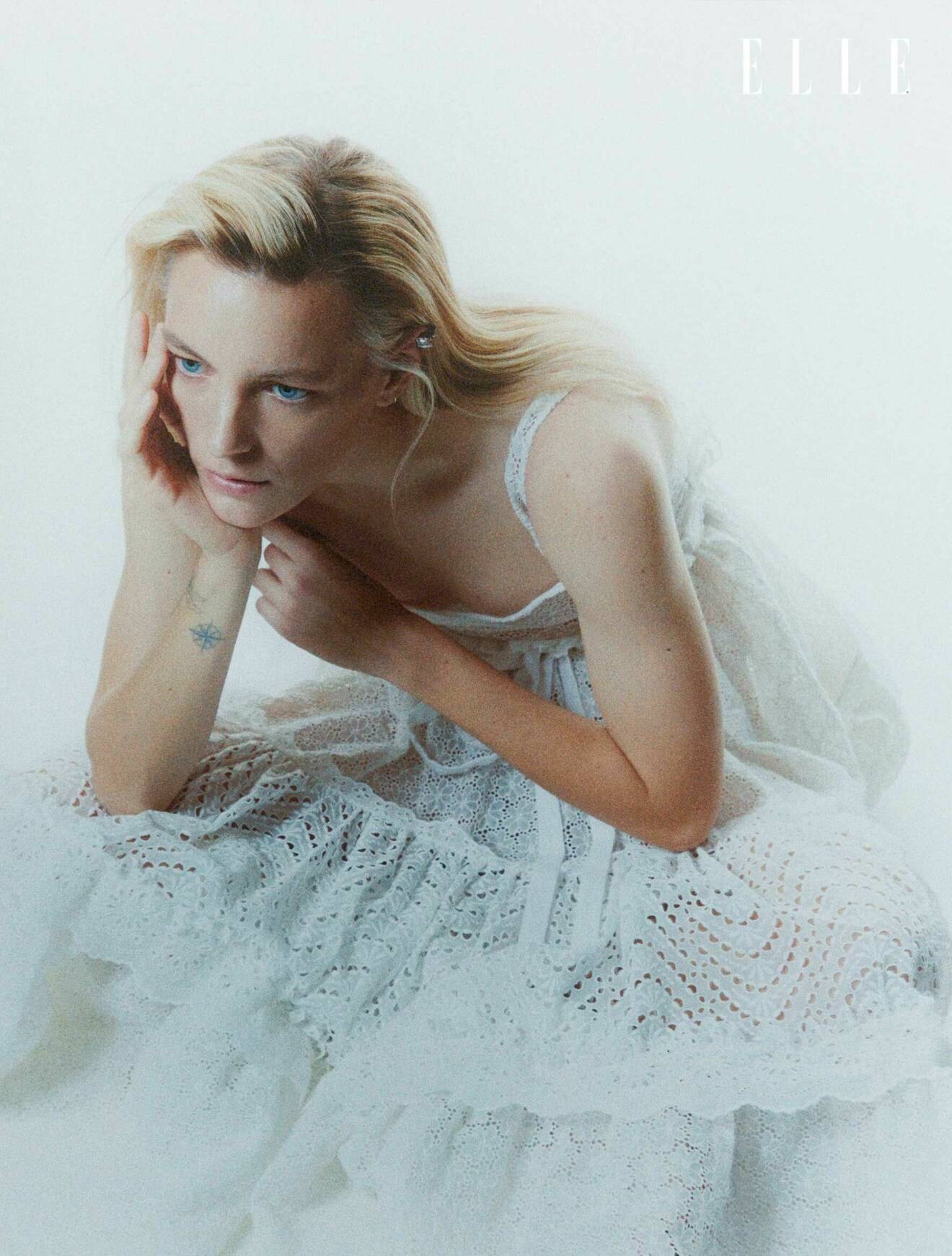Modellen har på sig en vit klänning med spetsdetaljer från Christian Dior.