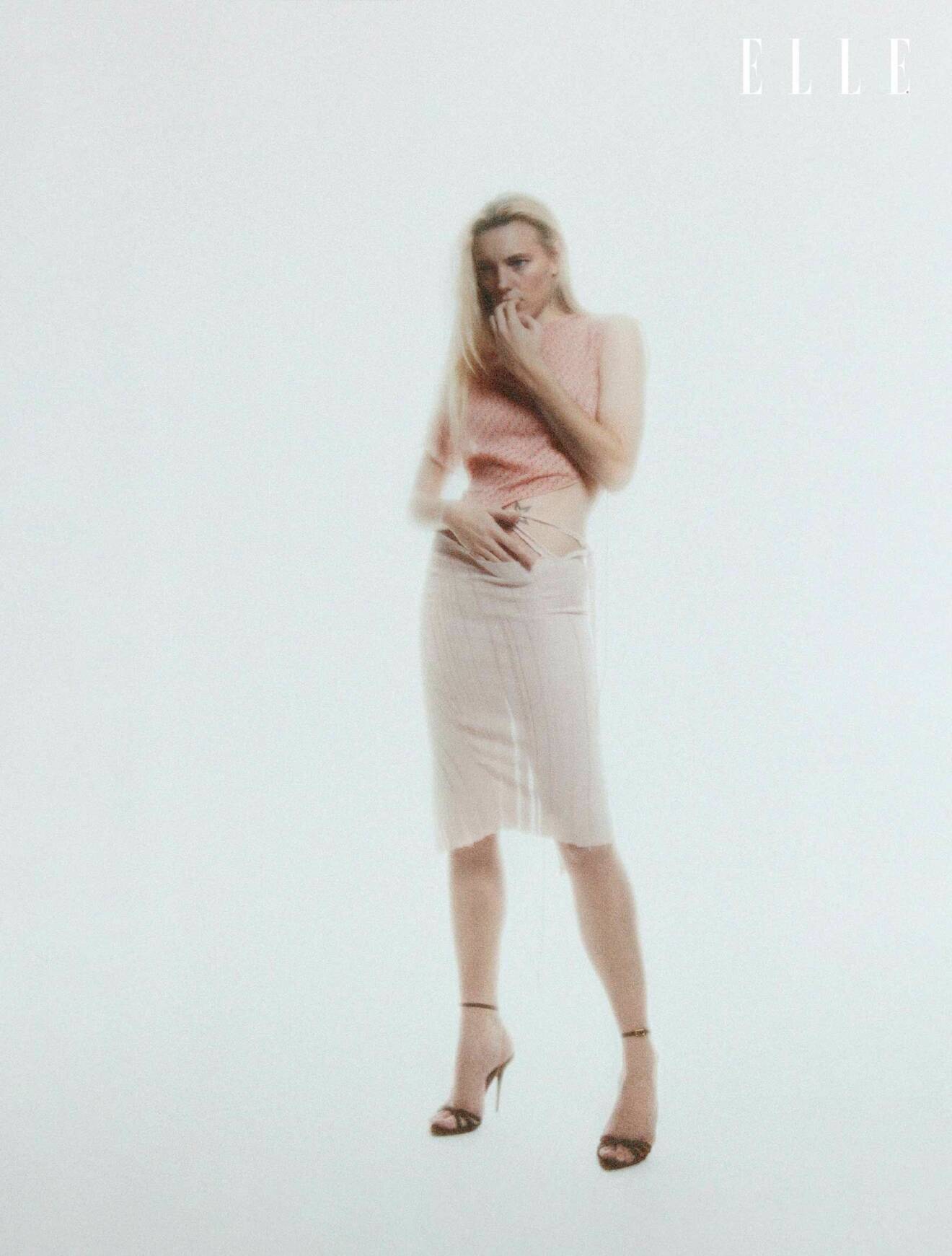 Modellen bär en rosa topp och en vit kjol, båda från Jade Cropper.