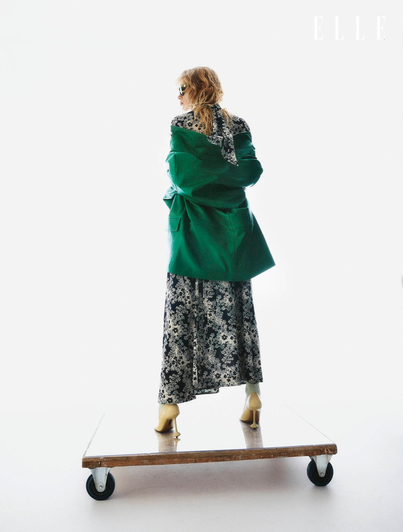 Modellen har på sig en blommig tröja med matchande kjol från Totême med en grön jacka från COS över