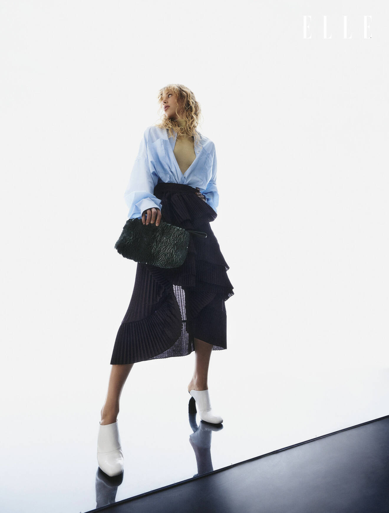 Modellen har på sig en ljusblå skjorta och en svart kjol med volang från Dries Van Noten