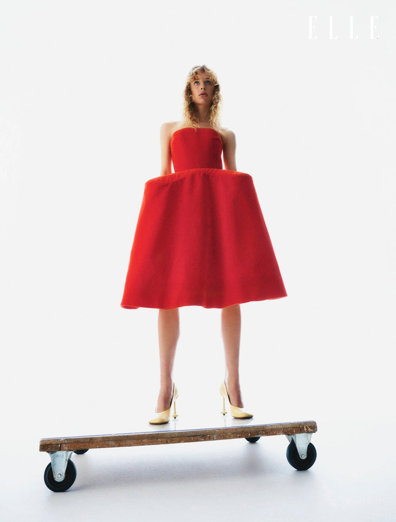 Modellen har på sig en axelbandslös röd klänning från Loewe