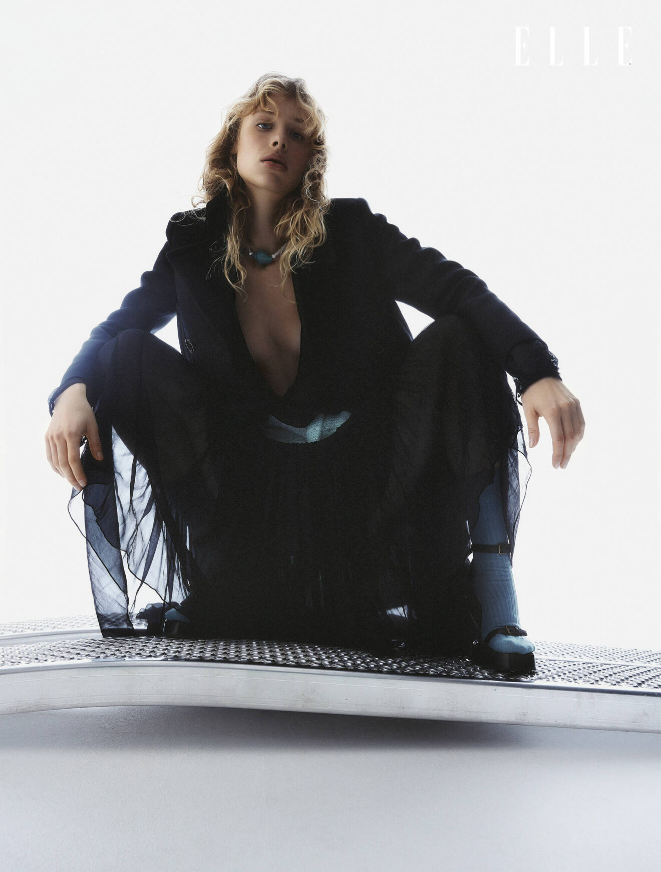 Fotomodellen har på sig en svart jacka och klänning, båda från Saint Laurent.