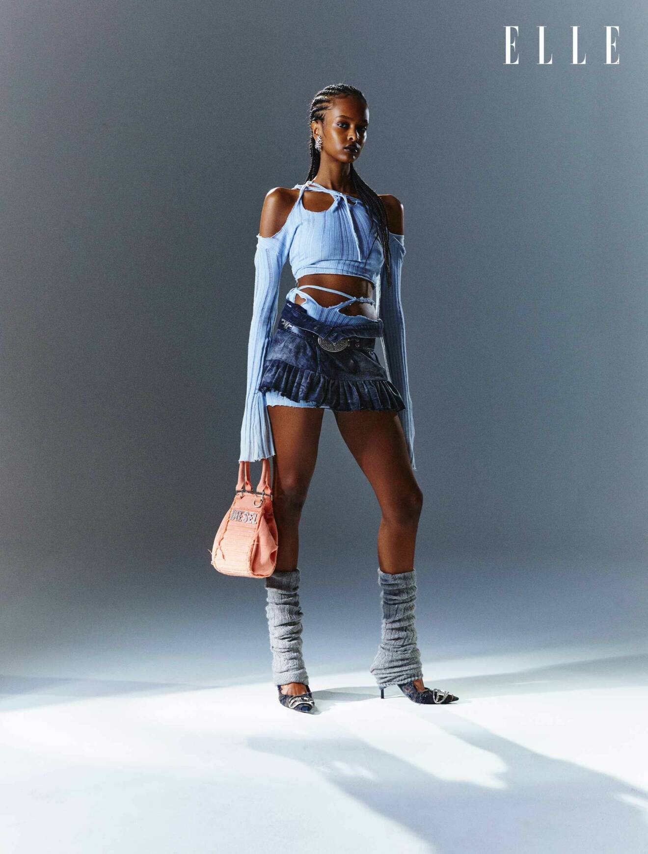 Fotomodellen har på sig en matchande ljusblå topp och kjol med cut out-detaljer och en minikjol i jeans.
