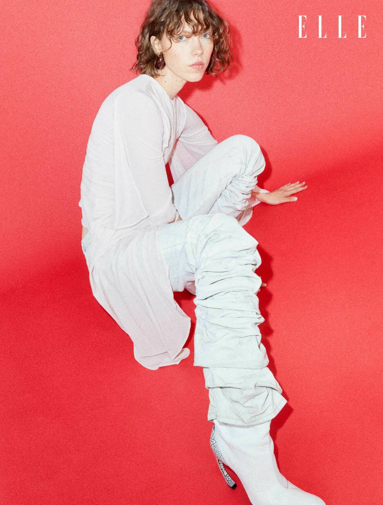 Fotomodellen bär en vit blus, vita byxor och vita skor, allt från Acne Studios.