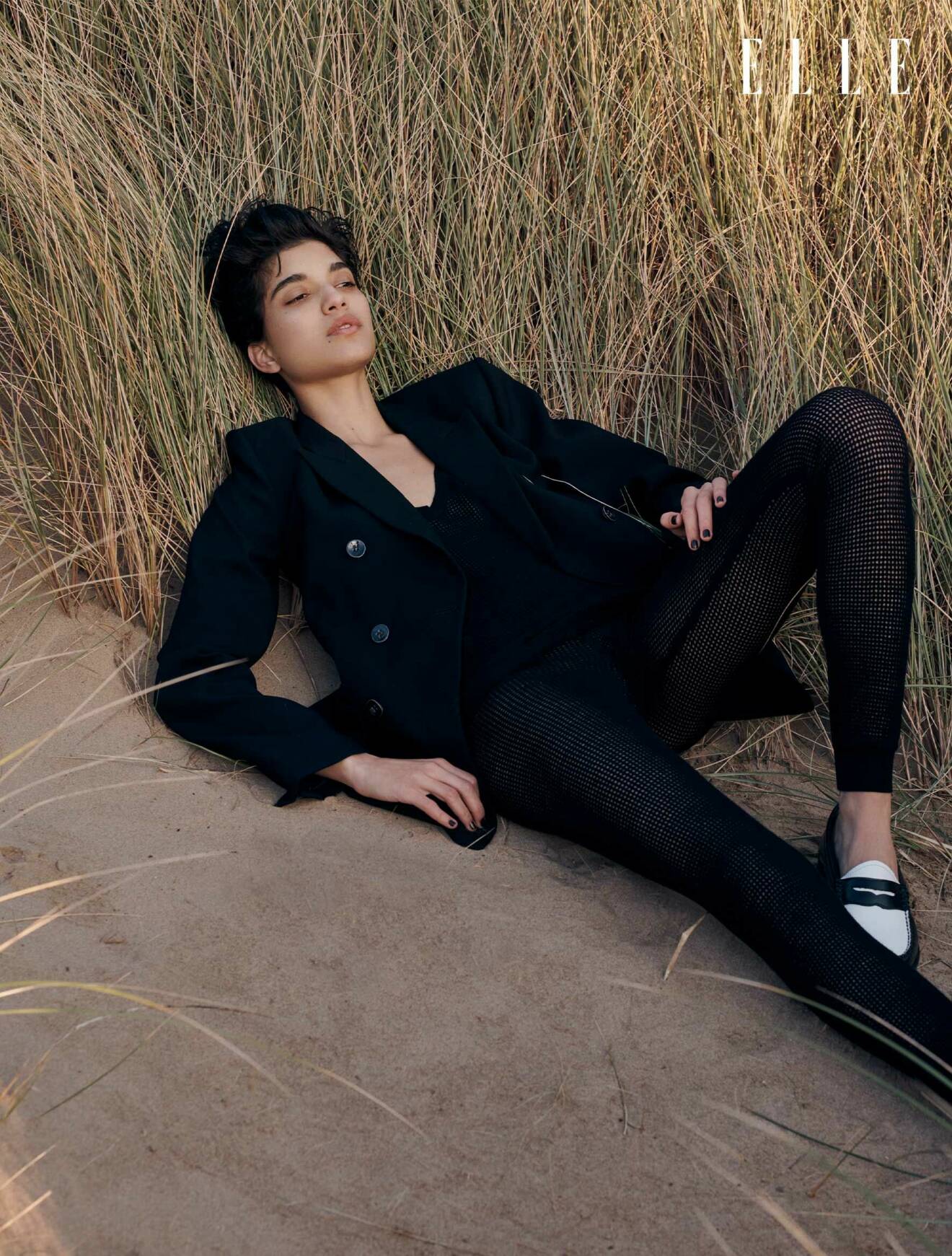 Modellen ligger på rygg i gräset, hon har på sig en svart kavaj, svart topp och leggings, allt från Chloé.
