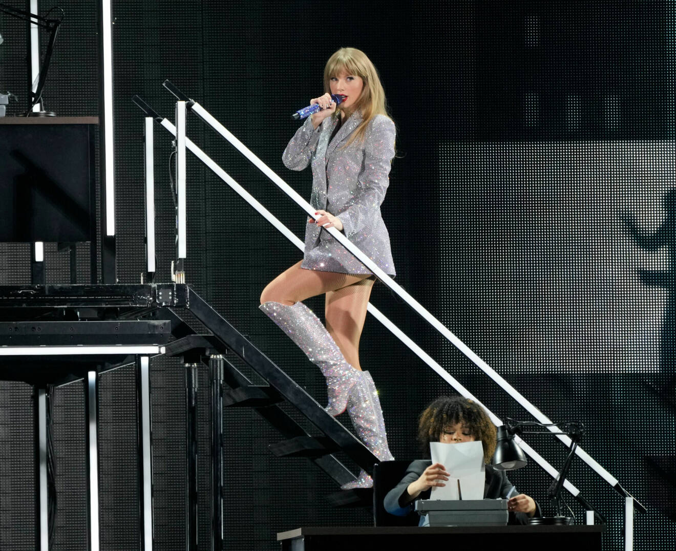 Taylor Swift som bytt om till en glittrig kavaj och glittriga stövlar.