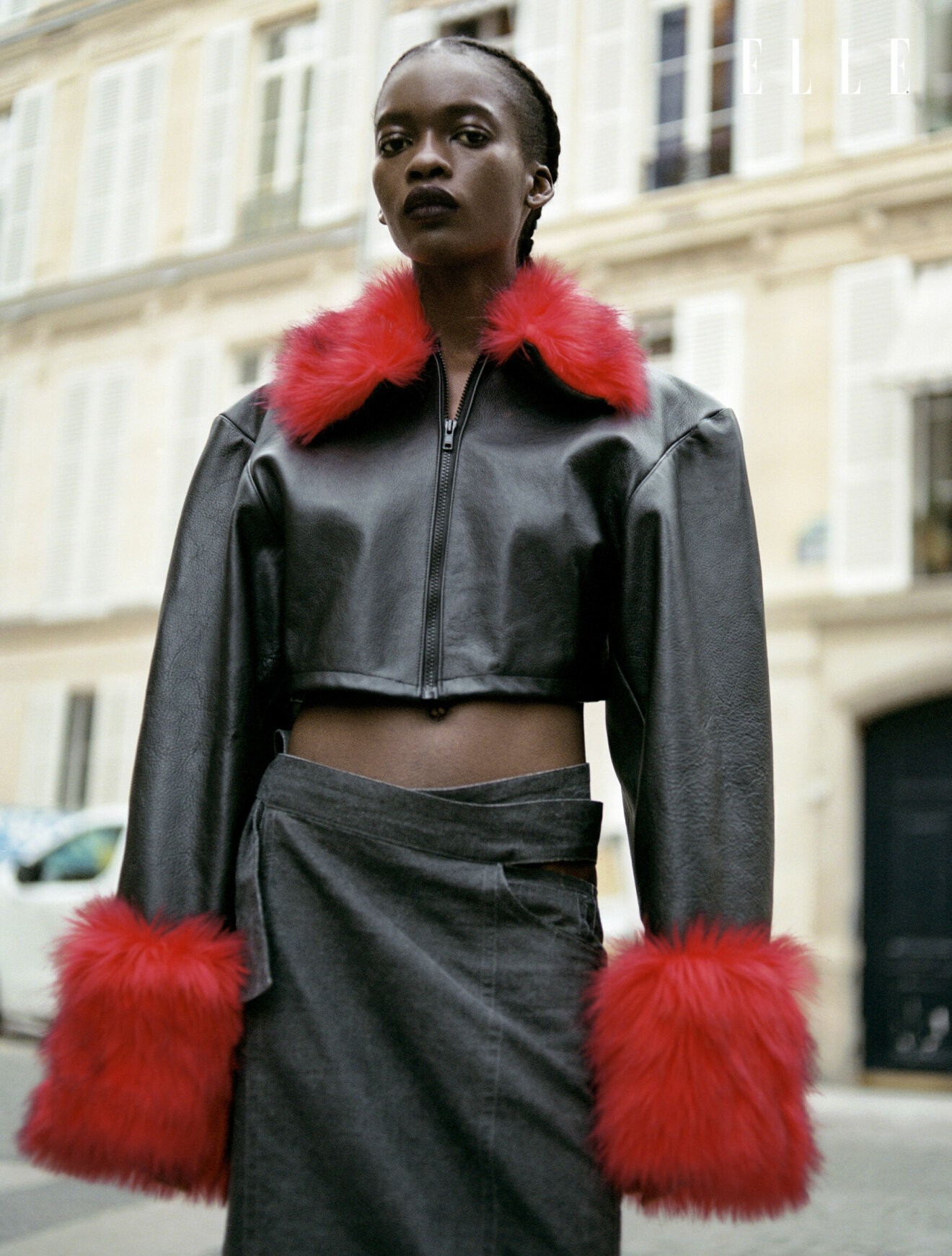Fotomodellen har på sig en svart kort jacka med röd fuskpäls i kragen och muddarna, från Jade Cropper.