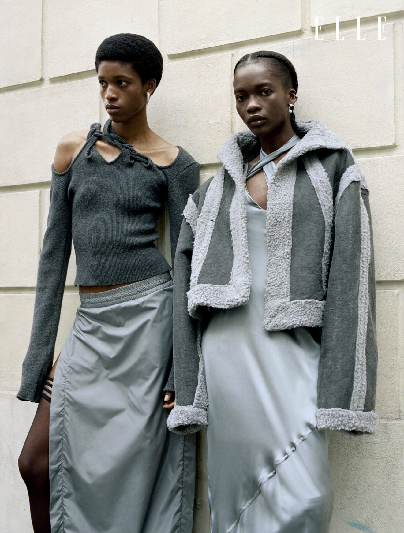 Modellen till vänster har på sig en stickad tröja med cut-outs och en grå kjol. Modellen till höger bär en grå jacka över en tunn långklänning, allt från Jade Cropper.