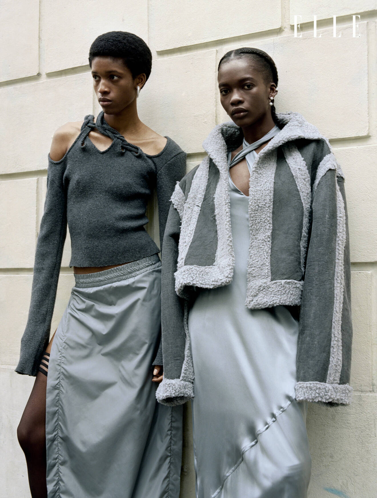 Modellen till vänster har på sig en stickad tröja med cut-outs och en grå kjol. Modellen till höger bär en grå jacka över en tunn långklänning, allt från Jade Cropper.