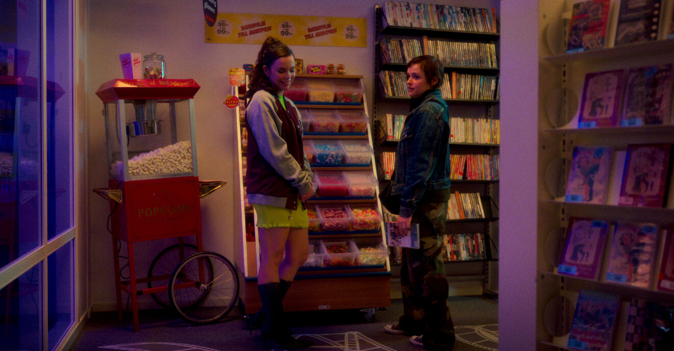 Två tjejer står bredvid varandra i en butik och ler.