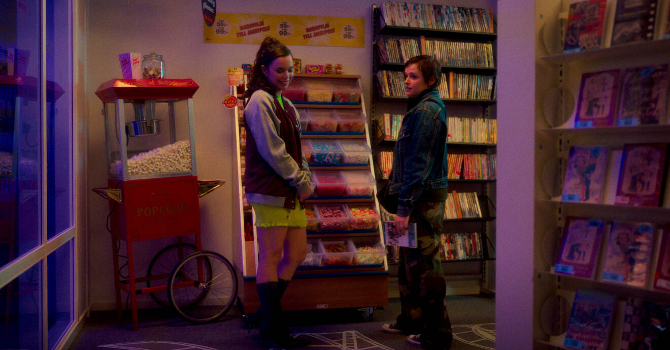 Två tjejer står bredvid varandra i en butik och ler.