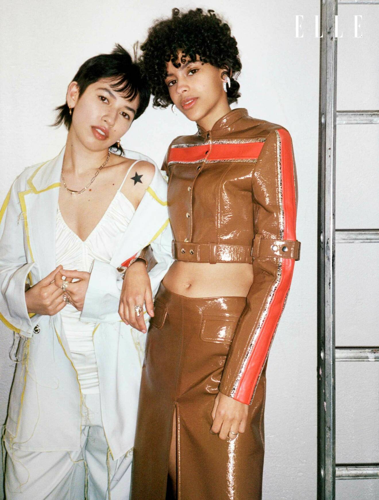 Anna Kim till vänster bär en vit blaxer, vit topp och vita byxor. Felicia har på sig matchande brun jacka och matchande kjol